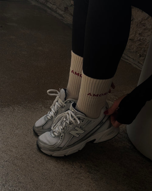 weiße „Amore“-Socken mit roten Herz-Noppen, kombiniert mit weißen New Balance Sneakern